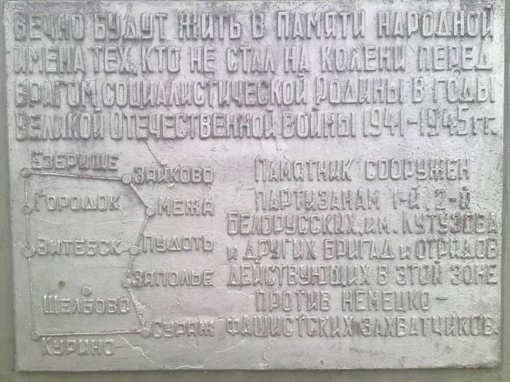  Щелбово, маёнтак (Цёсцінская воласць). Знак у памятника Партизану в деревне Щелбово,около озера Тиосто. Координаты памятника Широта 55.56444 С Долгота 30.50117 B